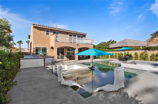 rear view of property with area for grilling, a swimming pool with hot tub, a balcony, and a patio