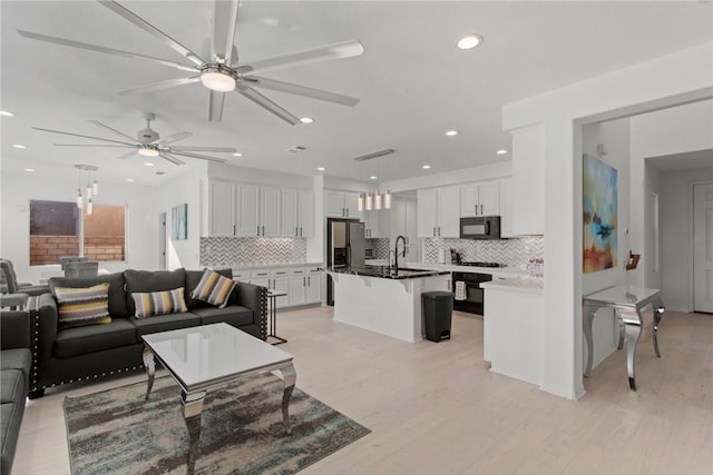 living room featuring light hardwood / wood-style floors, ceiling fan, and sink