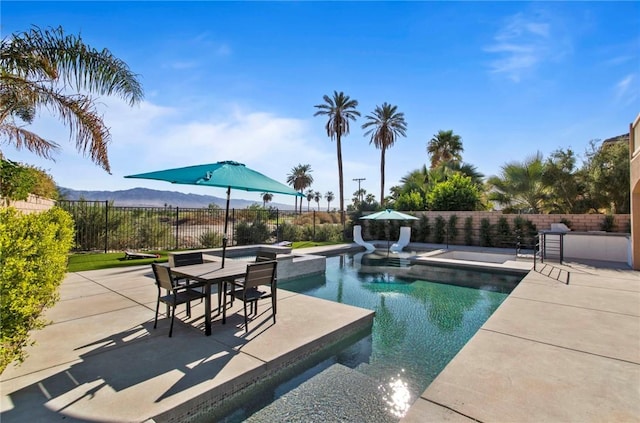 view of pool with an in ground hot tub, a mountain view, and a patio