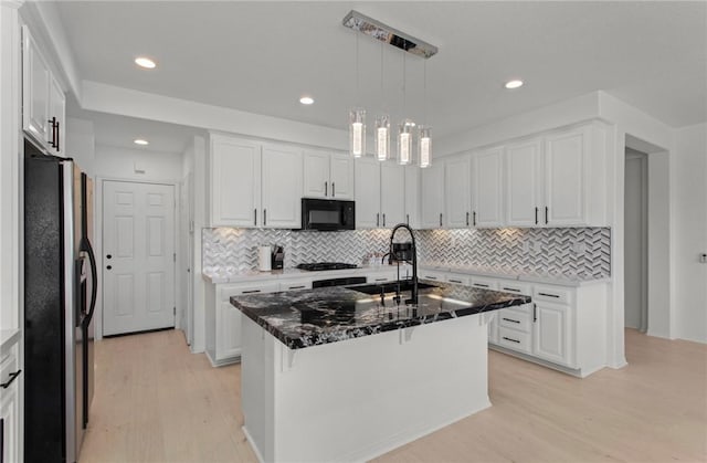 kitchen with a center island with sink, white cabinetry, light wood-type flooring, and stainless steel refrigerator with ice dispenser