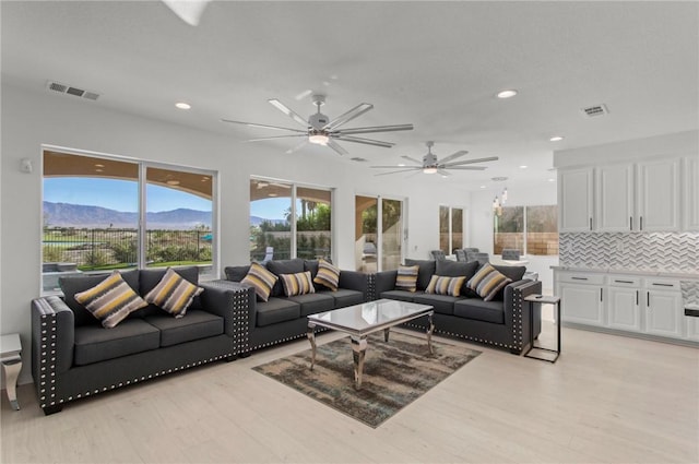 living room with a mountain view, ceiling fan, and light wood-type flooring