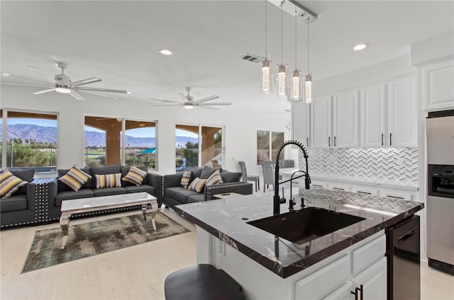 kitchen featuring white cabinets, a center island with sink, light hardwood / wood-style flooring, and sink