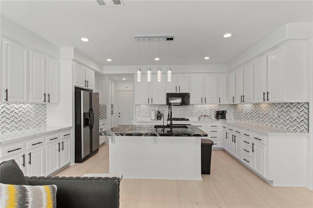 kitchen featuring light wood-type flooring, stainless steel refrigerator with ice dispenser, backsplash, and hanging light fixtures