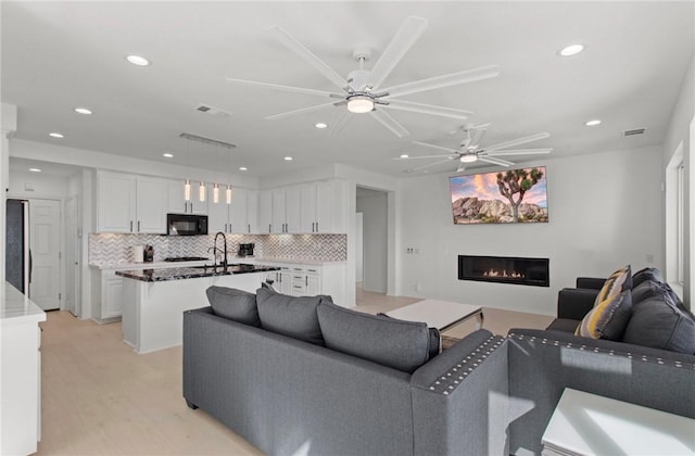 living room with ceiling fan and light hardwood / wood-style floors