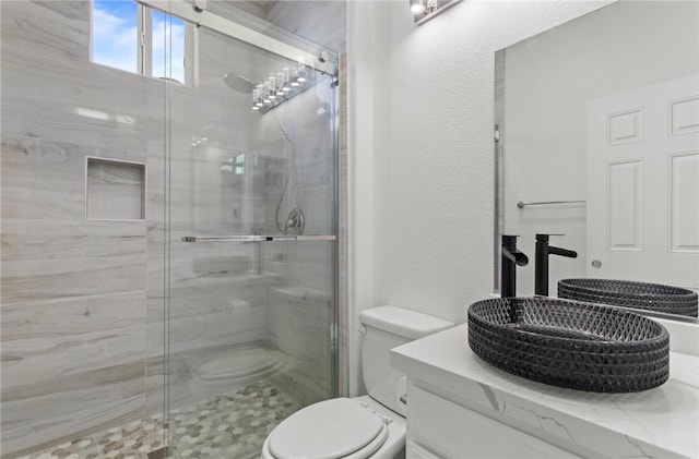 bathroom with vanity, toilet, and a shower with door