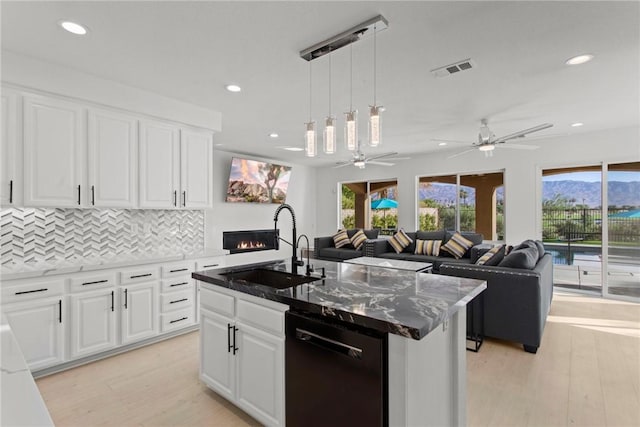 kitchen featuring dishwasher, light wood-type flooring, white cabinetry, and a kitchen island with sink