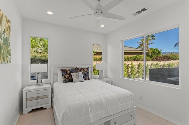 bedroom with ceiling fan, light hardwood / wood-style floors, and multiple windows