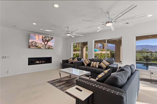 living room with plenty of natural light, light hardwood / wood-style floors, a mountain view, and ceiling fan