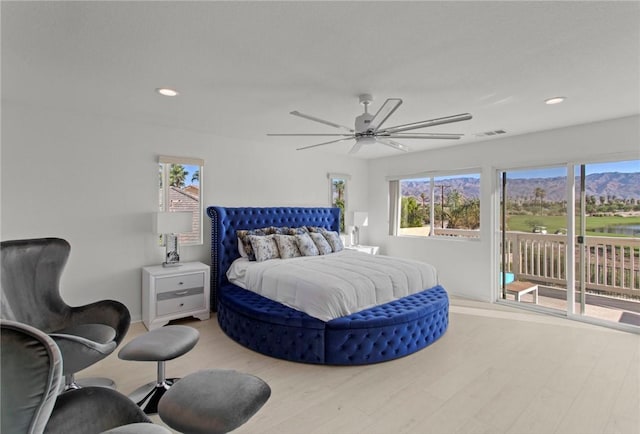 bedroom with ceiling fan, light hardwood / wood-style floors, a mountain view, and access to outside