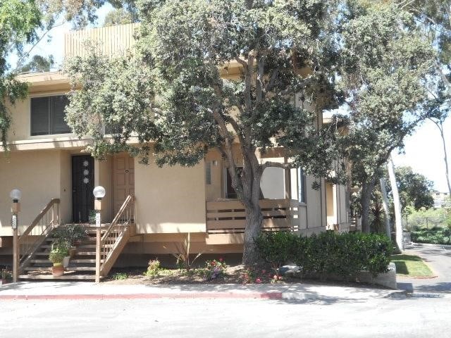 view of property hidden behind natural elements featuring stairway and stucco siding