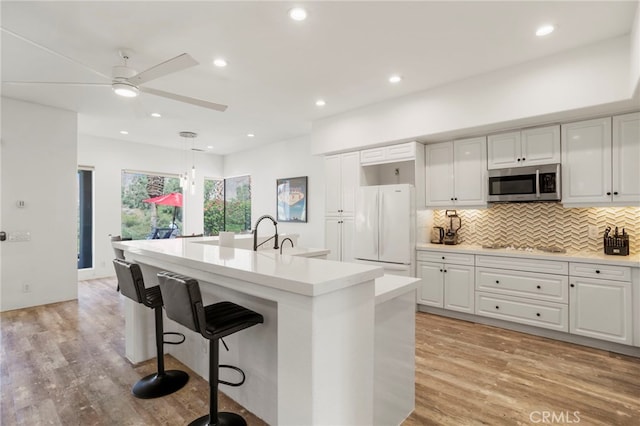 kitchen featuring decorative light fixtures, white fridge, light hardwood / wood-style floors, and white cabinetry