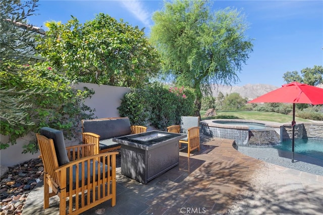 view of patio / terrace with pool water feature, a mountain view, a swimming pool with hot tub, and an outdoor living space with a fire pit