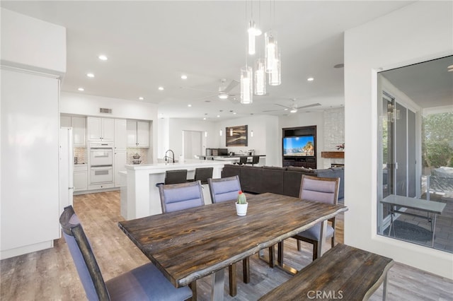 dining room featuring ceiling fan, light wood-type flooring, and sink