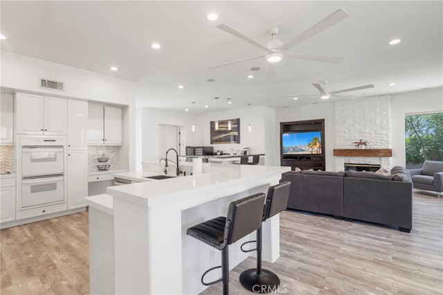 kitchen with a breakfast bar, light hardwood / wood-style floors, white cabinetry, and double oven