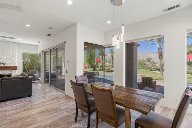 dining room with an inviting chandelier, a fireplace, and light hardwood / wood-style flooring