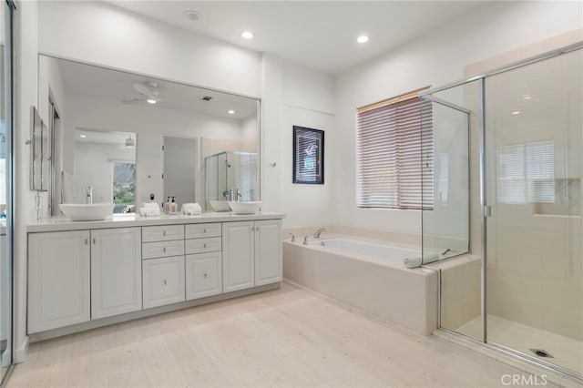 bathroom with wood-type flooring, vanity, ceiling fan, and independent shower and bath