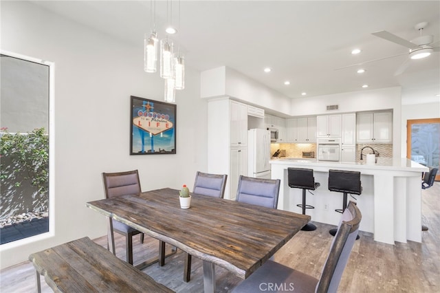 dining space with light wood-type flooring, ceiling fan, and sink