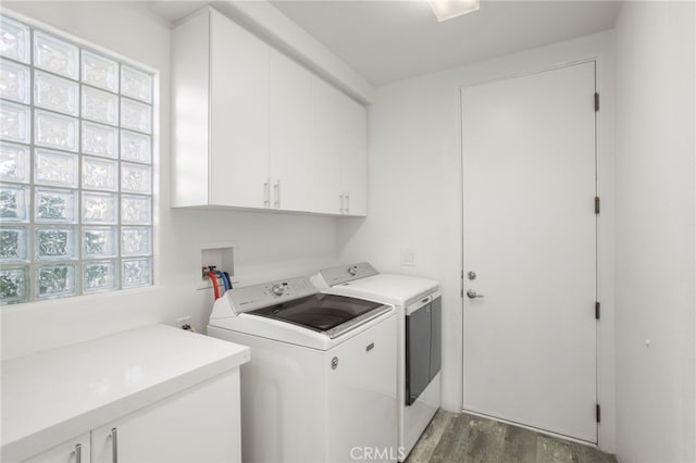 clothes washing area with washer and clothes dryer, cabinets, and dark hardwood / wood-style floors