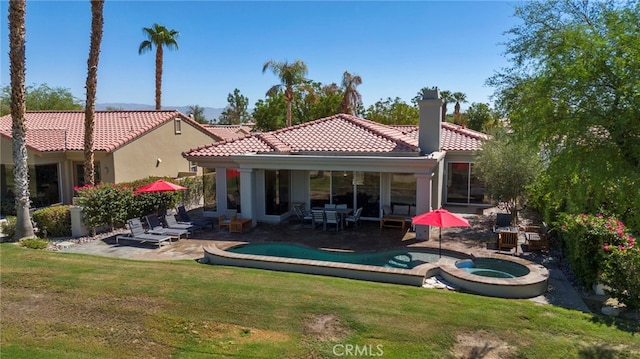 rear view of house featuring an in ground hot tub, a patio area, and a lawn