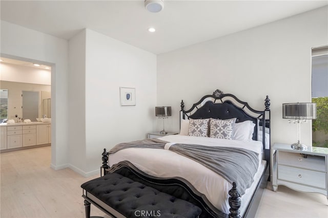 bedroom with ensuite bath and light wood-type flooring