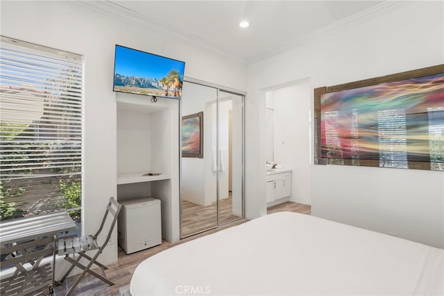 bedroom with light hardwood / wood-style floors, a closet, and crown molding