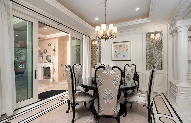 tiled dining room featuring ornamental molding, a chandelier, ornate columns, and a raised ceiling