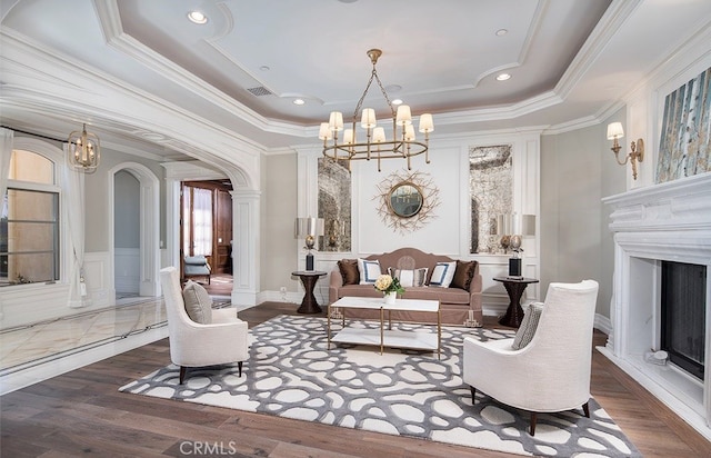 living room featuring crown molding, decorative columns, a raised ceiling, a chandelier, and dark hardwood / wood-style flooring