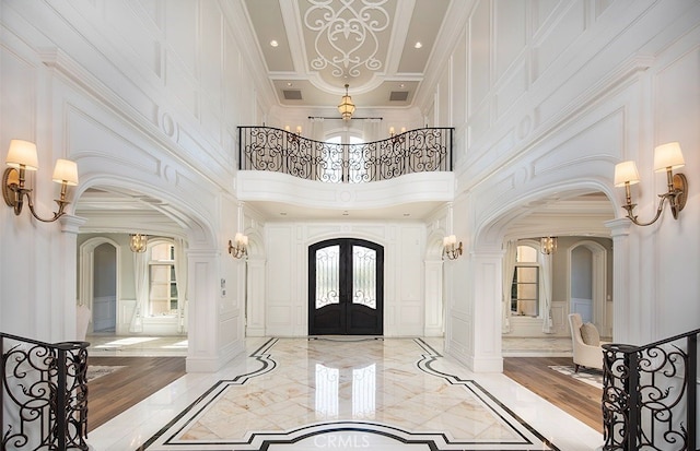 foyer with crown molding, light hardwood / wood-style flooring, and a towering ceiling