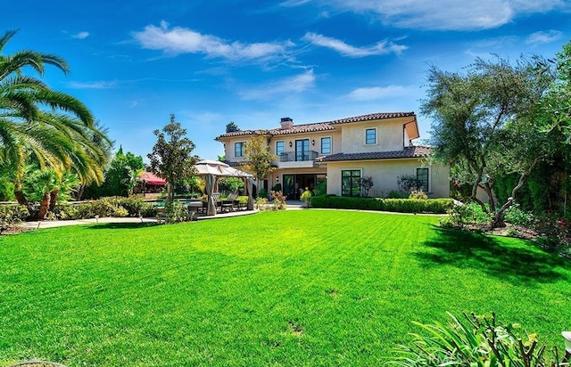 back of property featuring a gazebo, a patio, and a lawn