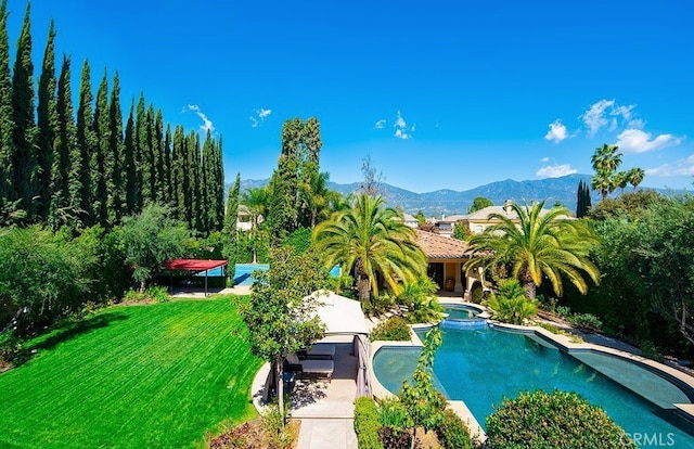 view of swimming pool featuring a yard, a mountain view, and a patio