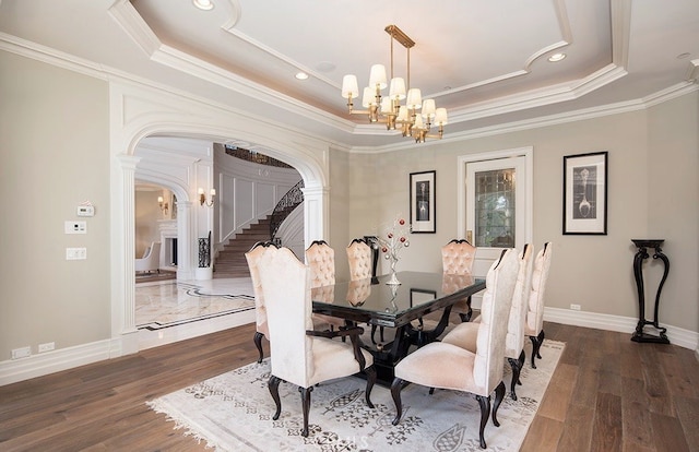 dining area with a notable chandelier, crown molding, a raised ceiling, and dark hardwood / wood-style flooring