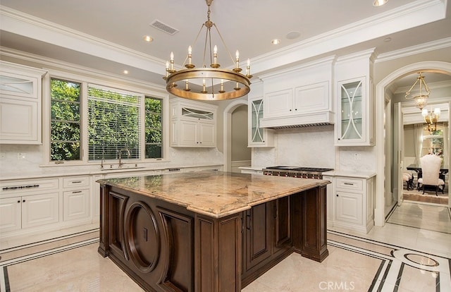 kitchen featuring sink, a kitchen island, ornamental molding, white cabinets, and decorative backsplash