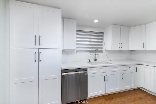 kitchen with light countertops, light wood-style flooring, dishwasher, white cabinetry, and a sink