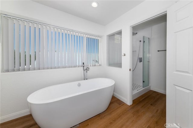 full bath with a freestanding tub, baseboards, wood finished floors, and a stall shower