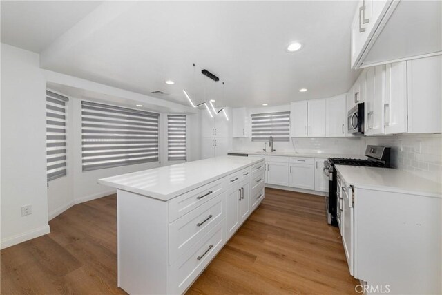 kitchen featuring a kitchen island, stainless steel appliances, light wood-type flooring, and white cabinetry