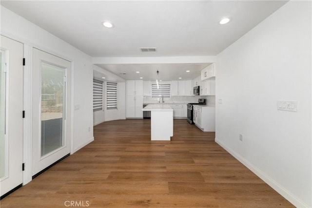 kitchen with white cabinets, wood finished floors, light countertops, and stainless steel appliances