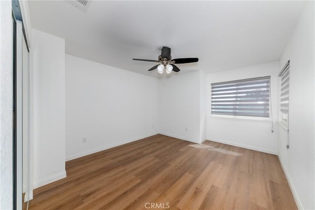 unfurnished bedroom featuring a ceiling fan, wood finished floors, baseboards, and visible vents