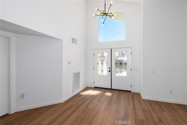 foyer entrance featuring french doors, a high ceiling, hardwood / wood-style flooring, and a healthy amount of sunlight