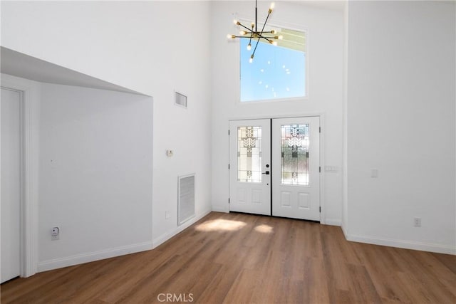 entrance foyer featuring baseboards, visible vents, a notable chandelier, and wood finished floors