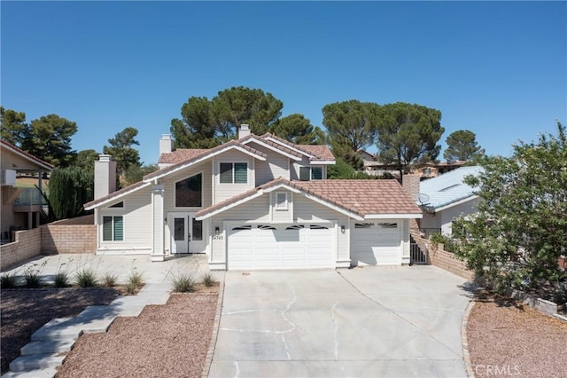 view of front of home with an attached garage, a chimney, fence, and concrete driveway