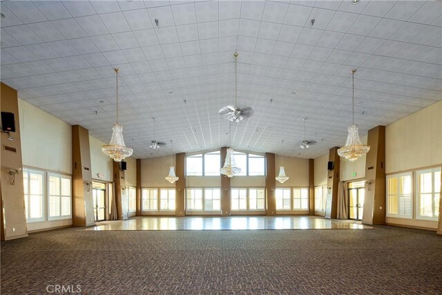 unfurnished room with carpet floors, plenty of natural light, high vaulted ceiling, and ceiling fan