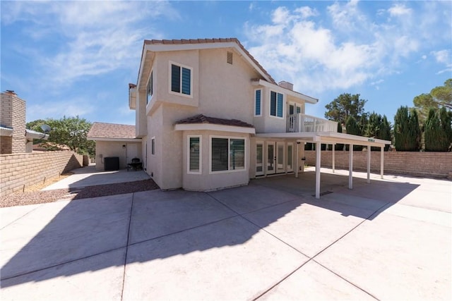 back of house featuring central air condition unit, stucco siding, fence, a patio, and a balcony