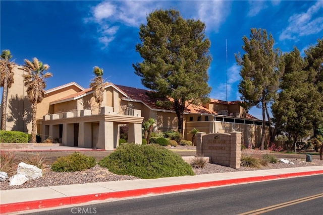 view of front of home with stucco siding, driveway, a garage, and a balcony