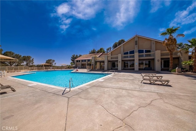 community pool featuring fence and a patio
