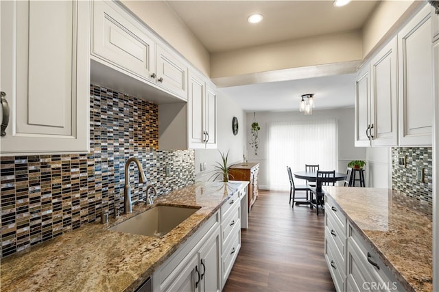 kitchen featuring dark hardwood / wood-style flooring, white cabinets, light stone counters, and sink