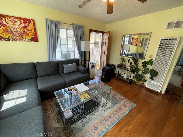 living room featuring a textured ceiling, ceiling fan, and dark wood-type flooring