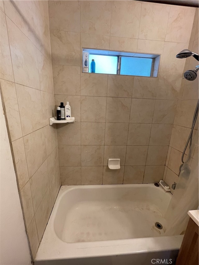 bathroom with tiled shower / bath and vanity