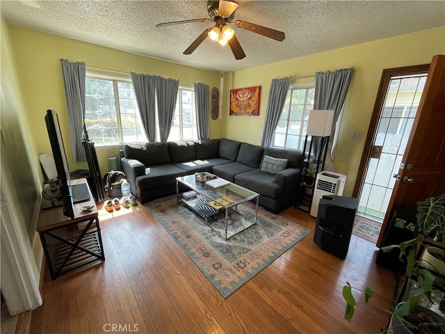 living room with ceiling fan, a textured ceiling, and hardwood / wood-style floors