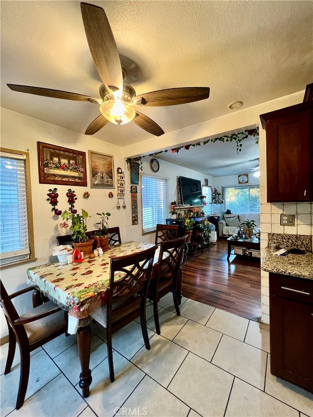 dining room with ceiling fan, a textured ceiling, and light wood-type flooring