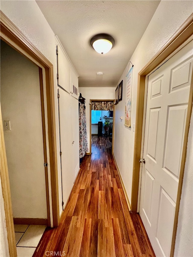 hallway with a barn door, a textured ceiling, and dark hardwood / wood-style floors